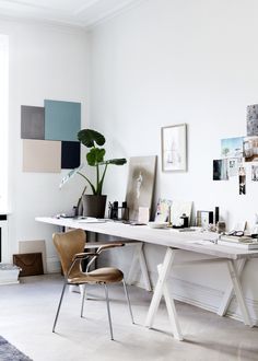 an image of a desk with chairs and pictures on the wall in front of it