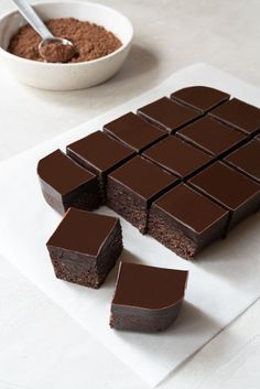 there are pieces of chocolate cake on the table next to some bowls and spoons