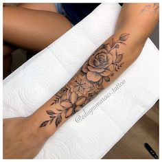 a woman's arm with flowers and leaves on it