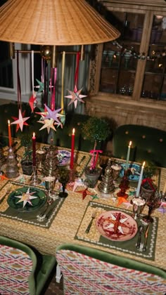 the table is set for christmas dinner with candles and plates on it, along with other holiday decorations