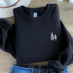 "Embrace the beauty of nature with our \"Pine Trees Embroidered Sweatshirt.\" This cozy crewneck sweater is more than just clothing; it's a tribute to the majesty of pine trees and the perfect gift for nature lovers, campers, and adventurers. 🌲 Pine Tree Majesty: Our sweatshirt features finely embroidered pine trees, capturing the essence of the great outdoors. It's a wearable work of art that brings the serenity of nature to your wardrobe. 🌳 Nature Lover's Choice: Whether you're embarking on a camping trip, hiking through the wilderness, or simply want to express your love for nature, this sweatshirt is your ideal companion. 🏞️ Comfort and Coziness: Crafted from soft and durable materials, our crewneck sweatshirt ensures both warmth and comfort. It's perfect for staying snug on cool ev Black Long Sleeve Top With Custom Embroidery, Black Tops With Custom Embroidery For Winter, Black Top With Custom Embroidery For Winter, Embroidered Crew Neck Winter Tops, Casual Winter Tops With Custom Embroidery, Casual Tops With Custom Embroidery For Winter, Casual Custom Embroidered Tops For Winter, Mummy Sweatshirt, Halloween Embroidery