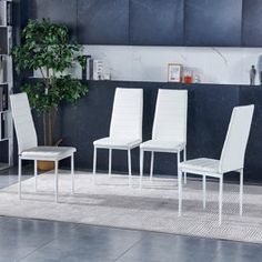 four white chairs sitting in front of a book shelf