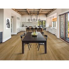 a dining room table and chairs in front of a large open kitchen with wood flooring