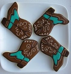 four decorated cookies in the shape of cowboy's boots on a white platter