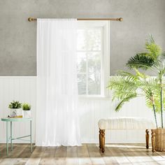 a living room with a white curtain and potted plants