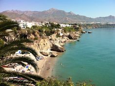 a beach with people on it and mountains in the backgroung, as seen from above