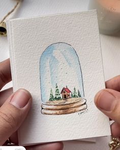 a hand holding up a card with a snow globe on it's front and bottom