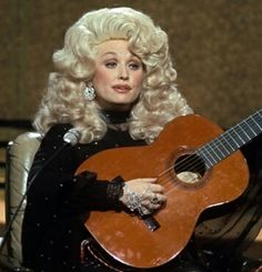 dolly monroe holding an acoustic guitar while sitting in a chair