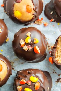 chocolate candies with candy toppings on top of them and one bite taken out