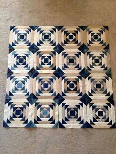 a blue and white quilt sitting on top of a floor next to a carpeted floor