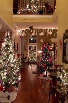 christmas trees are decorated with lights and snowflakes on the ceiling in this hallway