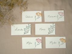 four place cards with watercolor flowers on them and the names of each card are shown