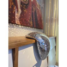 a mirror ball sitting on top of a wooden table in front of a wall painting