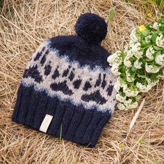 a blue and white knitted hat next to a bouquet of flowers on the ground