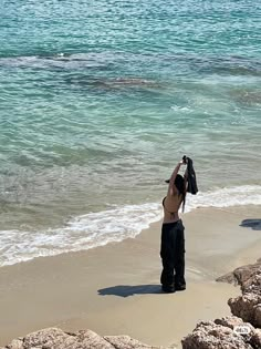 a woman standing on top of a sandy beach next to the ocean