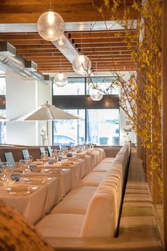 a long table set up with white linens and place settings for people to eat