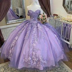 a purple ball gown with flowers on the skirt is displayed in front of a mirror