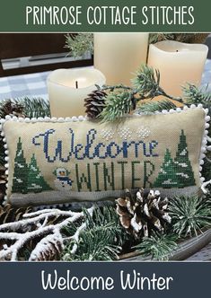 a welcome winter pillow with pine cones and candles