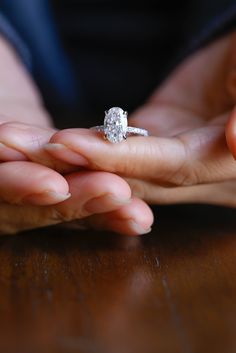 a close up of a person's hand holding a diamond ring