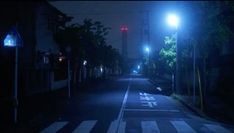 an empty street at night with no cars on the road and one person walking down it