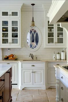 a kitchen with white cabinets and an oval mirror on the wall above the stove top