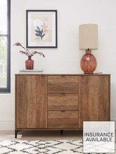 a wooden cabinet with two vases sitting on top of it next to a lamp