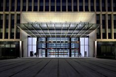 the entrance to an office building lit up at night with lights shining on it's windows