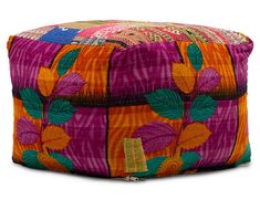 an orange, pink and green patchwork pouff with leaves on it's sides