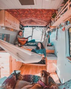 two women sitting in the back of a camper with hammocks hanging from the ceiling