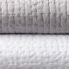 two white bedspreads stacked on top of each other