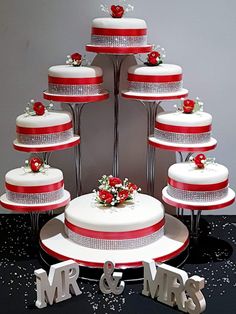 a wedding cake with red and white frosting on top is surrounded by silver letters