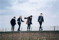 four people standing on top of a brick wall