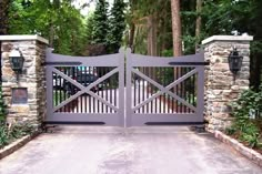 a driveway gate with stone pillars and gates