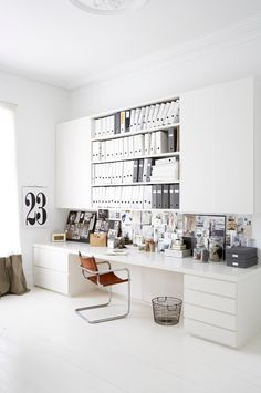 an office with white walls and shelves filled with books