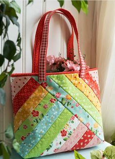 a multicolored tote bag sitting on top of a table next to a potted plant