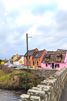 a river running through a small town with colorful houses on the side and cars parked in front of it