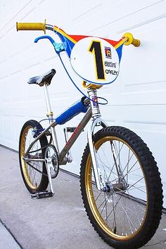 a blue and yellow bike parked in front of a white garage door with the number one on it