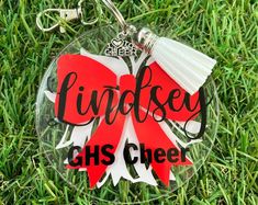 a glass ornament with the words lindsey ghs cheer on it in black and red