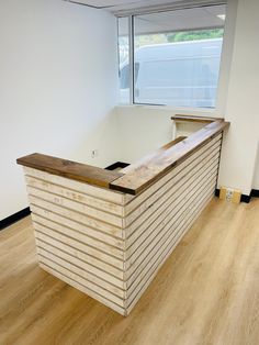 a wooden counter sitting in the middle of a room with hard wood flooring and white walls