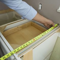 a person measuring the width of a drawer with a tape measure on top of it