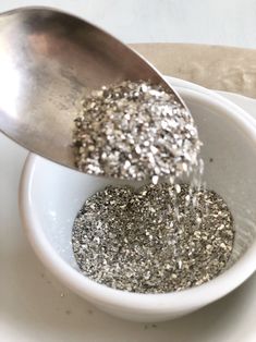 a spoon pouring silver glitter into a white bowl