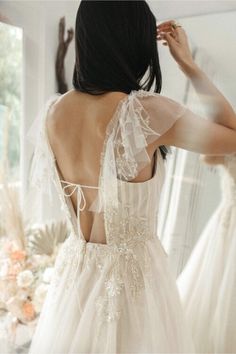 the back of a woman's wedding dress in front of a mirror