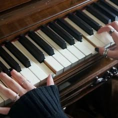 two hands are playing the piano with one hand on the keys, while the other is sitting down