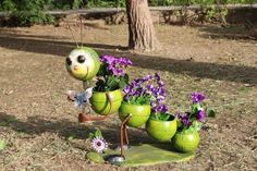 a green planter with purple flowers in it and an insect figure on the ground