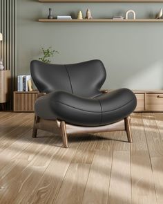 a black leather chair sitting on top of a hard wood floor next to a shelf