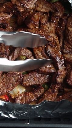 the meat is being prepared and ready to be cooked in the oven with tongs