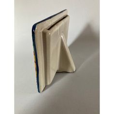 a ceramic bookend with a blue strip on the front and bottom part, sitting on a white surface