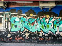 graffiti is painted on the side of a brick wall in an alleyway under a bridge