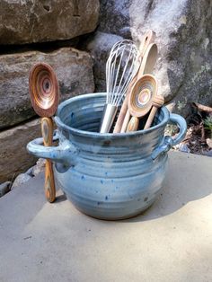 a blue bowl filled with whisk and spoons on top of a table