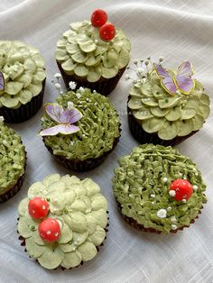 six cupcakes decorated with green frosting and flowers on a white table cloth